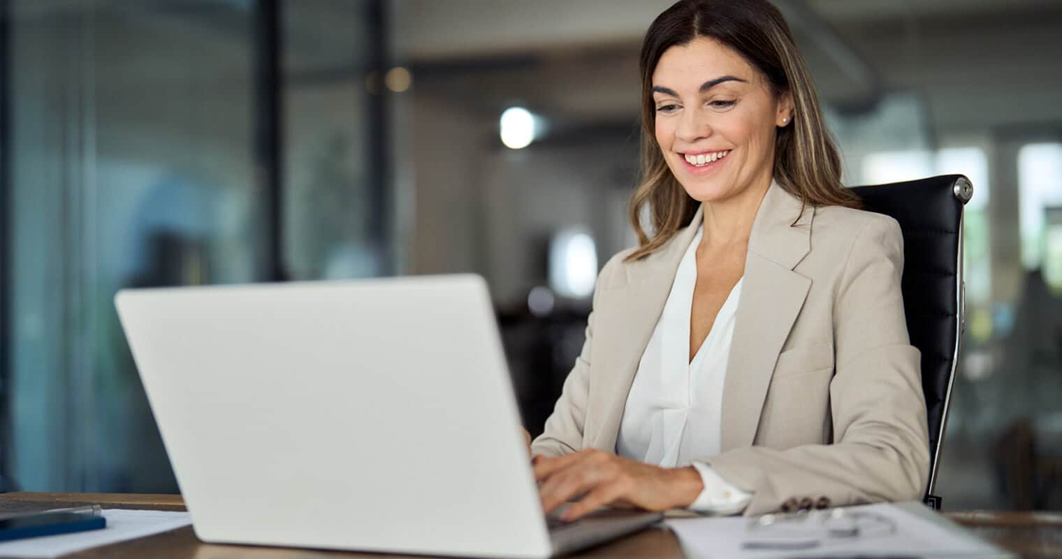 Smiling woman working on laptop, emphasizing enterprise data governance.