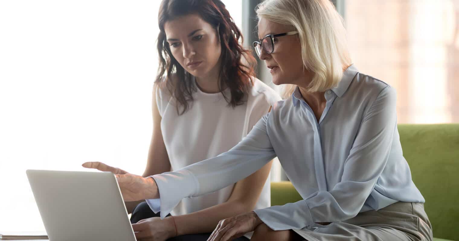 Two women discussing data warehouse vs operational database on laptop